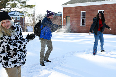 Students playing in the snow on campus in the winter.