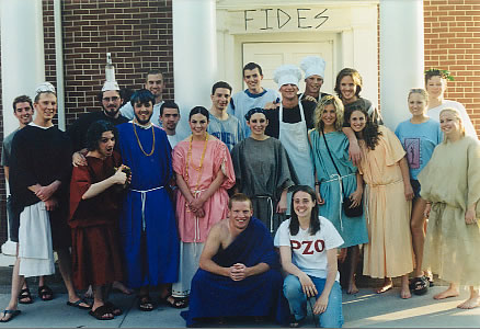 the cast and crew of Aulularia, in costume, posing for a group photo outside the building used as backdrop for the play. 