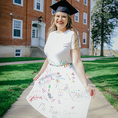 Teacher education program graduate M Thiele in a dress decorated by her student-teaching class.