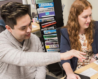 Cornell students consulting together on laptops