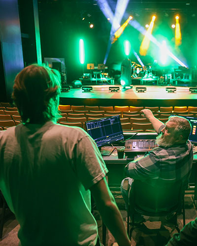 Professor and student in theatre lighting design course with hands-on practice.