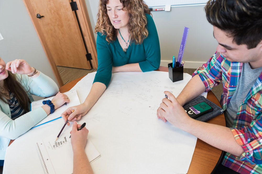 Cornell students and faculty member around a table brainstorming solutions