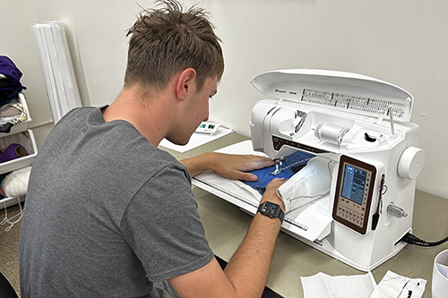 student using sewing machine in maker space