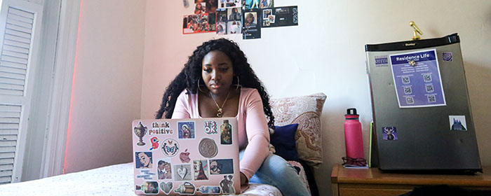 Black female student with laptop in residence hall