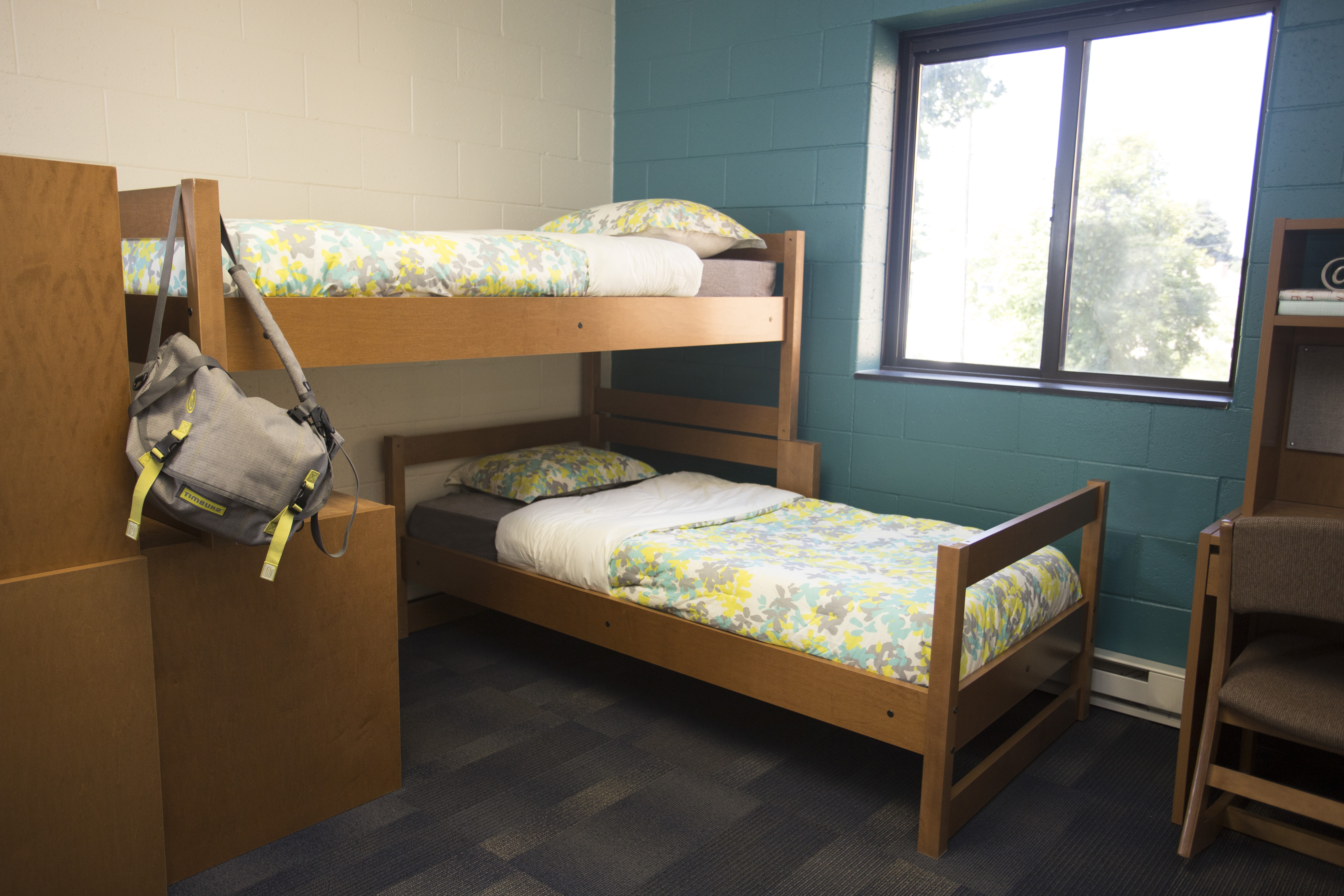 A bed lofted sideways with a desk and other bed