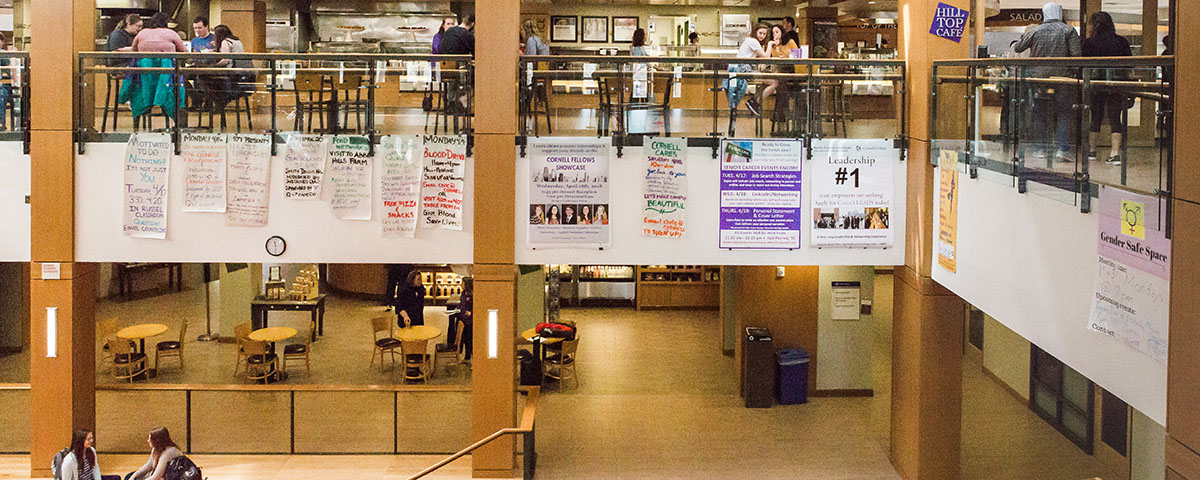 Students hang posters about events in Thomas Commons